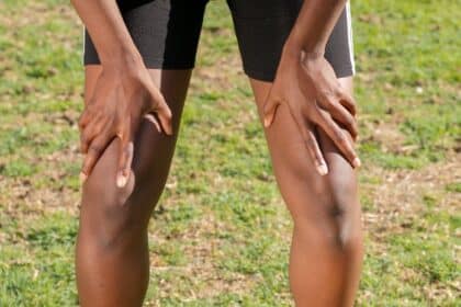 Close-up of an athlete resting after a workout, grasping knees outdoors.